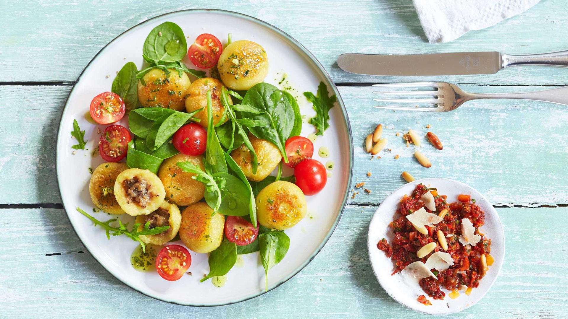 Ein Teller mit einem Pfannigericht auf einem hellblauen Holztisch.