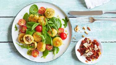 Ein Teller mit einem Pfannigericht auf einem hellblauen Holztisch.