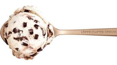 Ein goldener Eis-Löffel mit dem Schriftzug "Löffelzarter Genuss" mit einer Kugel Eis.