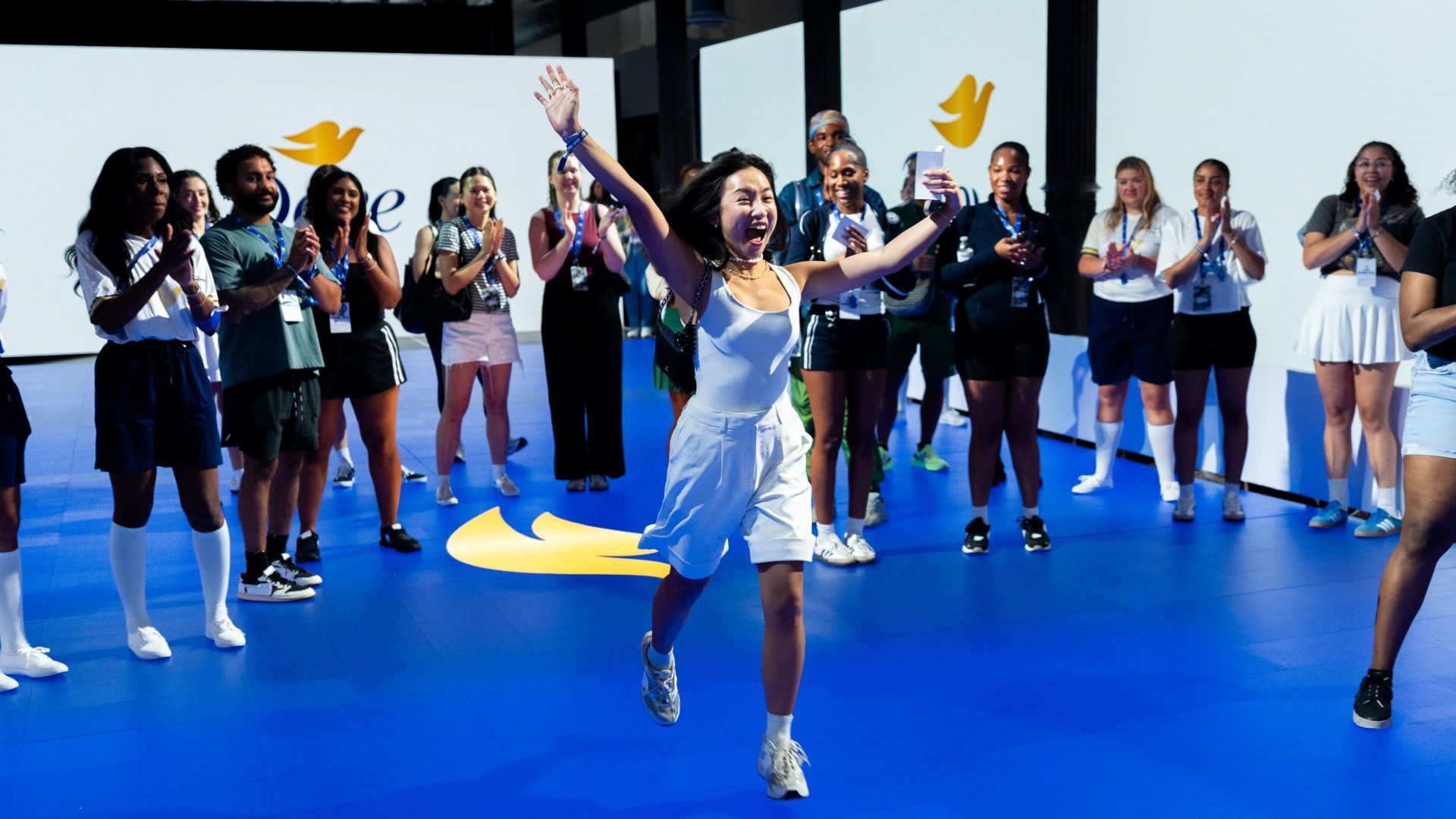 Frauen nehmen im House of Fresh von Unilever an einer Dove-Choreografie. Im Vordergrund läuft eine Frau voller Freude und streckt dabei jubelnd die Arme in die Höhe.