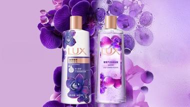 Lux-Produkte mit spritzigem Duft, die auf einer Unterlage aus lilafarbenen Blüten und Blütenblättern liegen