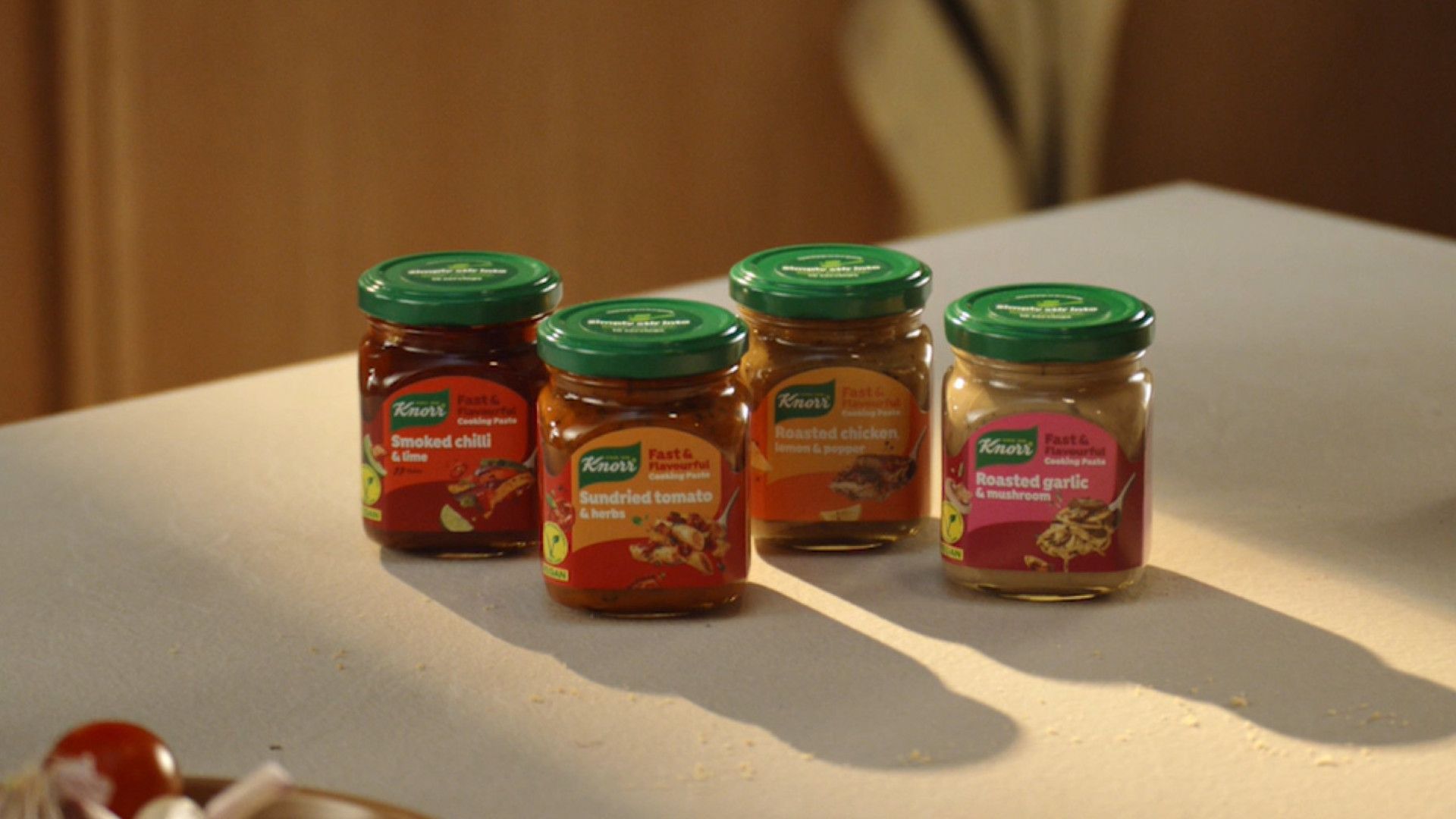 Vier Gläser mit Knorr Kochpasten stehen auf einem weißen Küchentisch. KI hat die Entwicklungszeit für dieses Produkt halbiert.