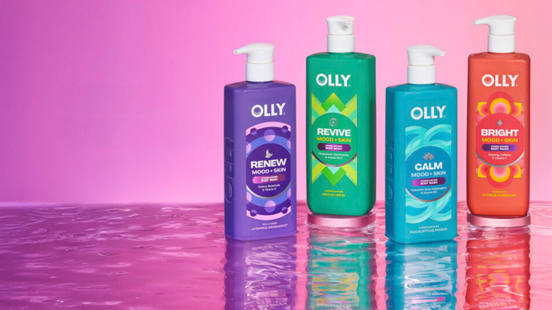 Vier farbige Flaschen von Olly Mood + Skin Waschlotion auf einer reflektierenden Oberfläche vor einem Hintergrund mit rosafarbenem Farbverlauf.